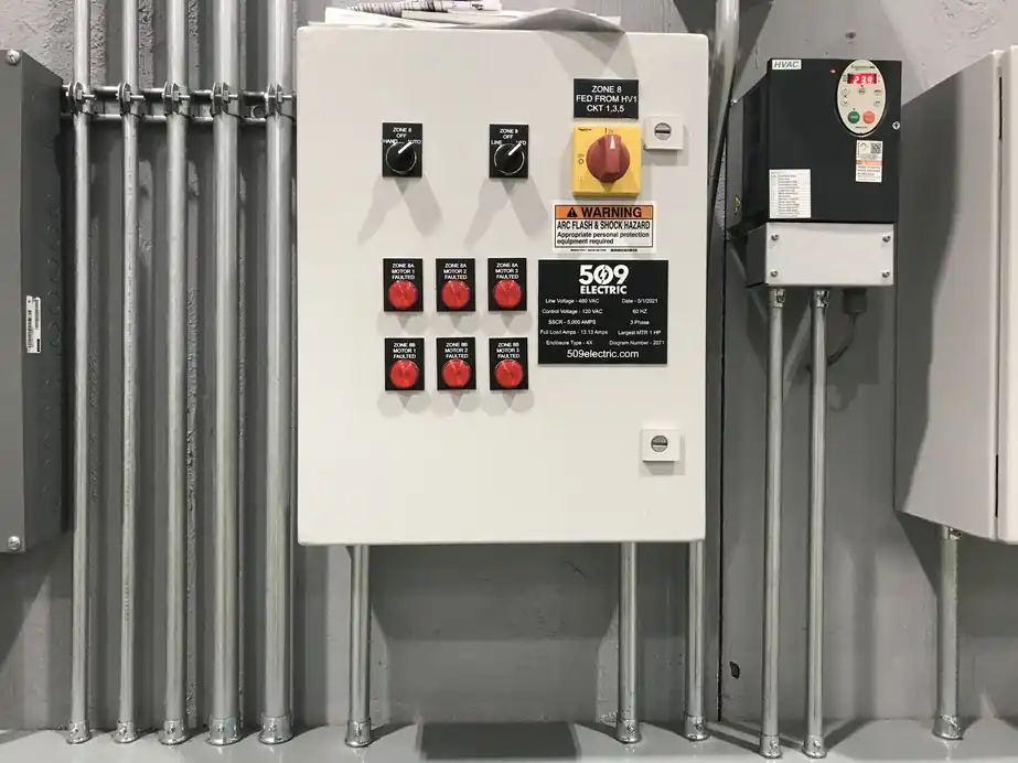 Custom control panel with a 509 Electric nameplate, red pilot lights and a disconnect on a packhouse wall