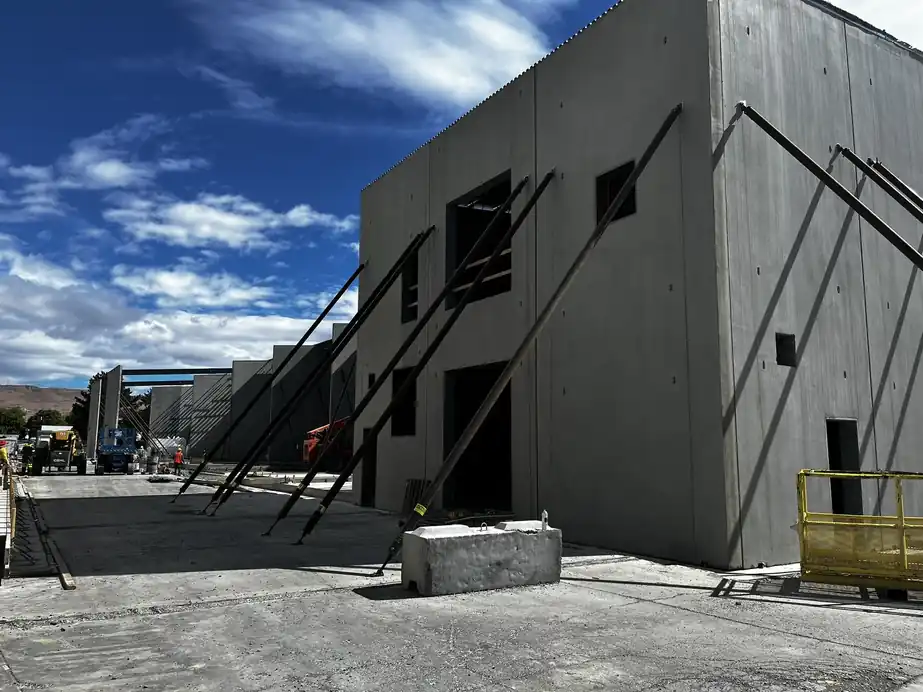 Concrete tilt-up warehouse walls braced on a new commercial site under a blue Yakima Valley sky